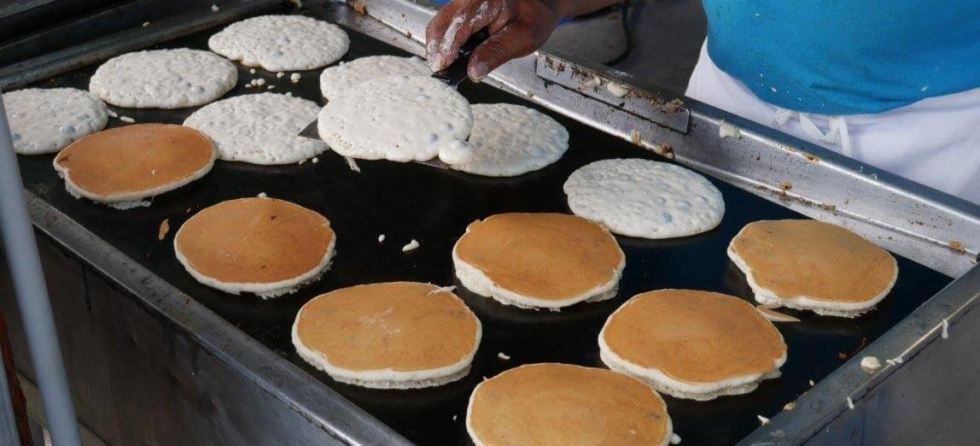 Blueberry pancakes cooking on a griddle