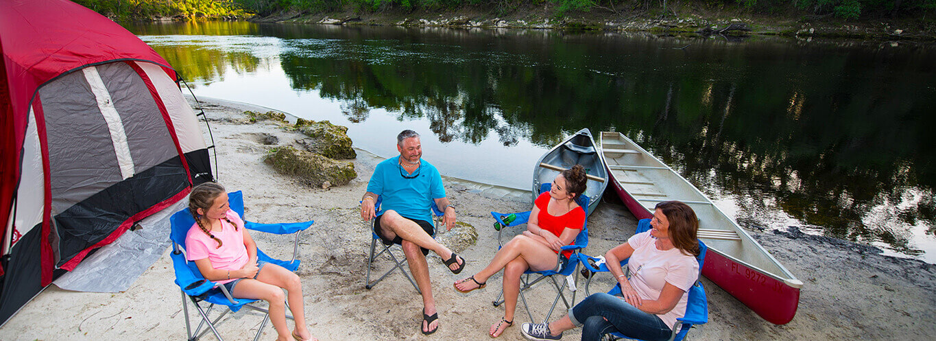 campers sitting in chairs by river in suwannee campground