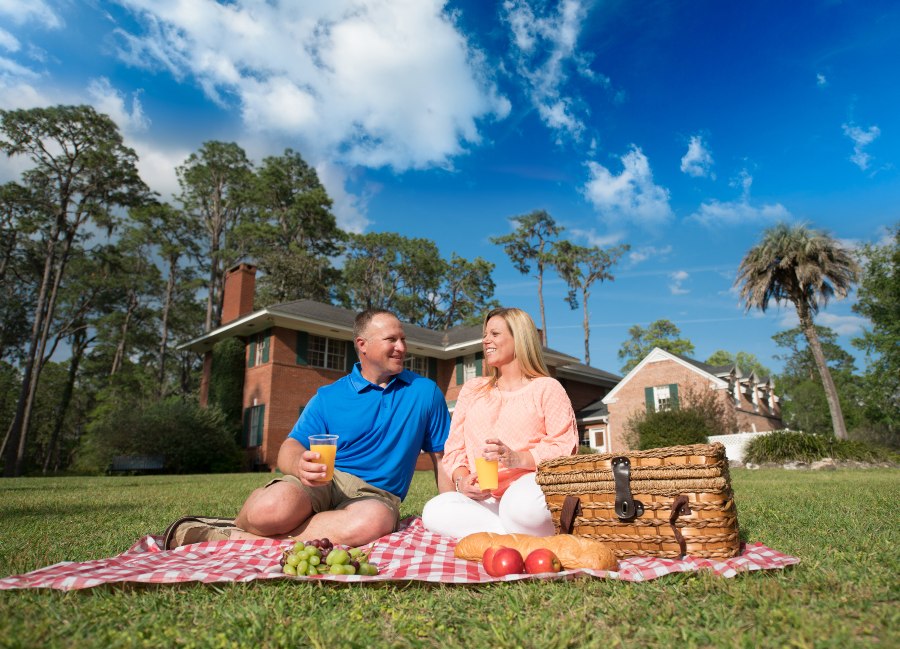 Couple enjoys a picnic on the grounds of Heritage Park with the historic home in the background
