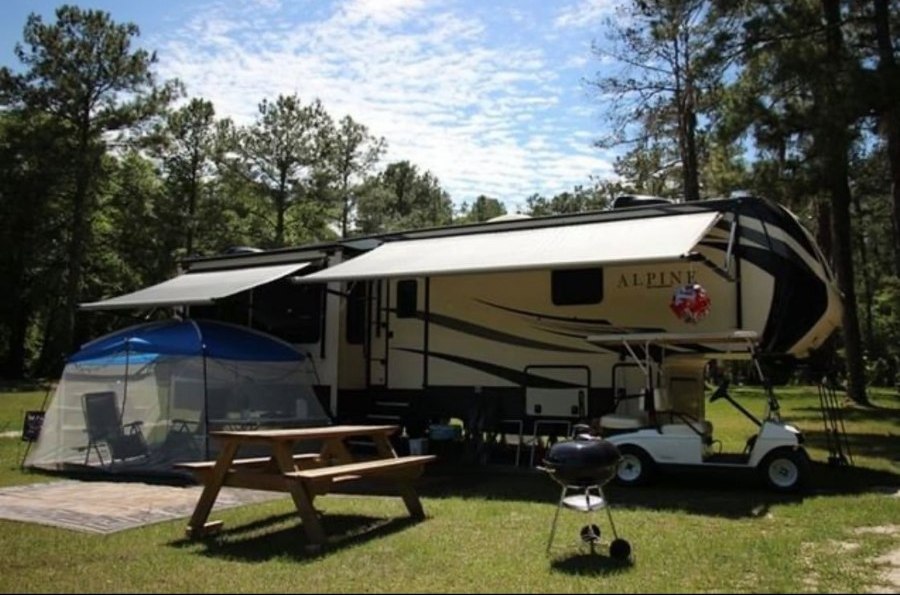 An RV and picnic area sit nestled amidst a forested campground at the Spirit of Suwannee Music Park in Florida.