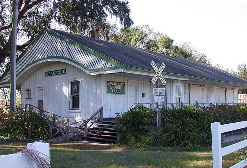 The white facade of the Branford Railroad Depot is seen, nestled near the historic banks of the Suwannee River.