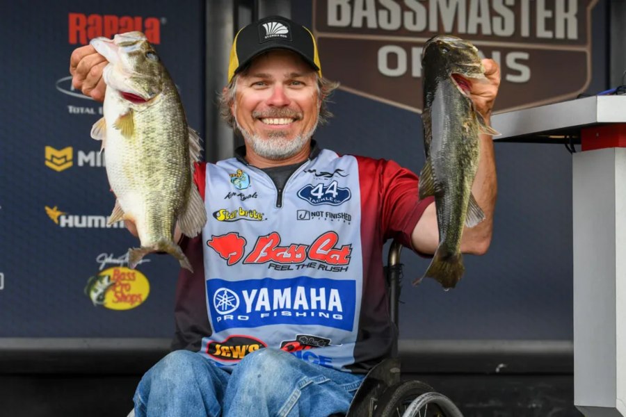 Local fishing guide Ron Ryals hold two bass aloft on the stage of a fishing competition on the Suwannee River.