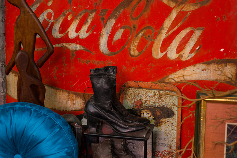 A vintage pair of boots rests in front of a classic Coca-Cola sign at an antique shop in Suwannee County, Florida.