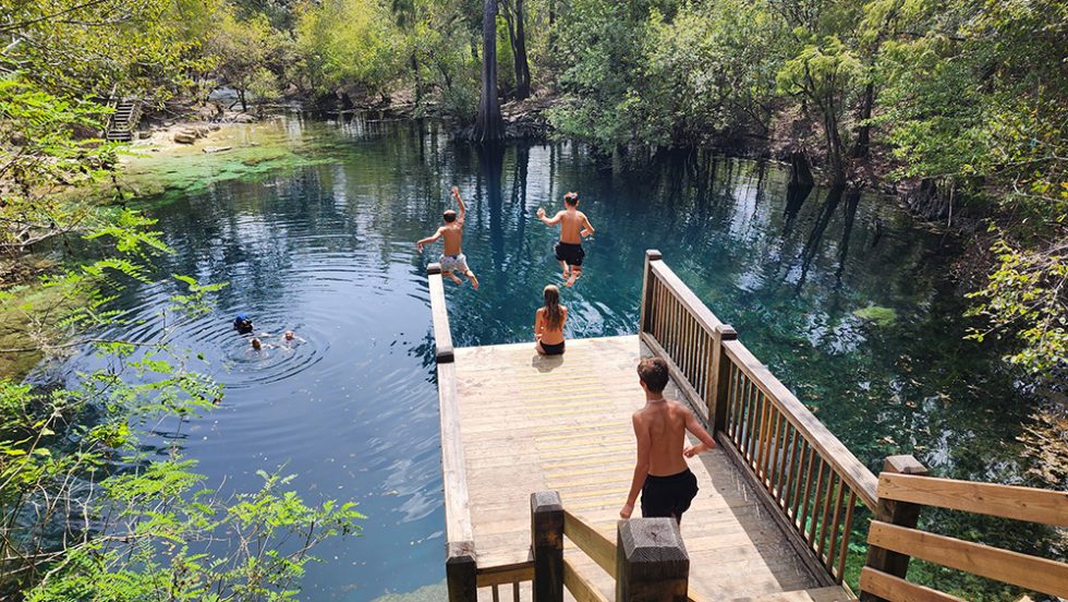 Children jump from a platform and land in the blue water of Royal Springs in Suwannee County, Florida.