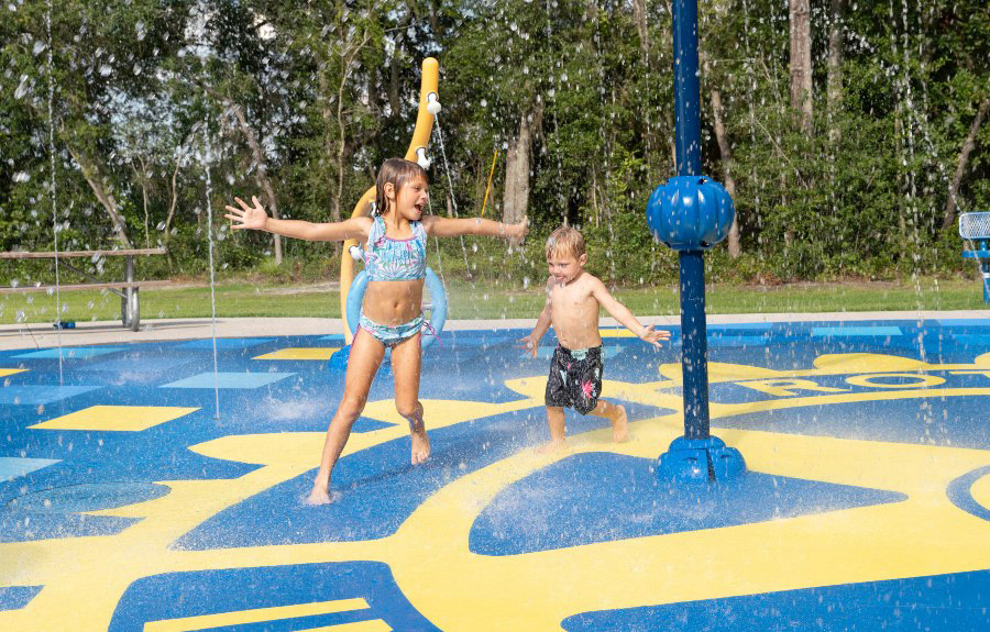 A young boy and girl play in the water at a community splash pad in Suwannee County, Florida. 