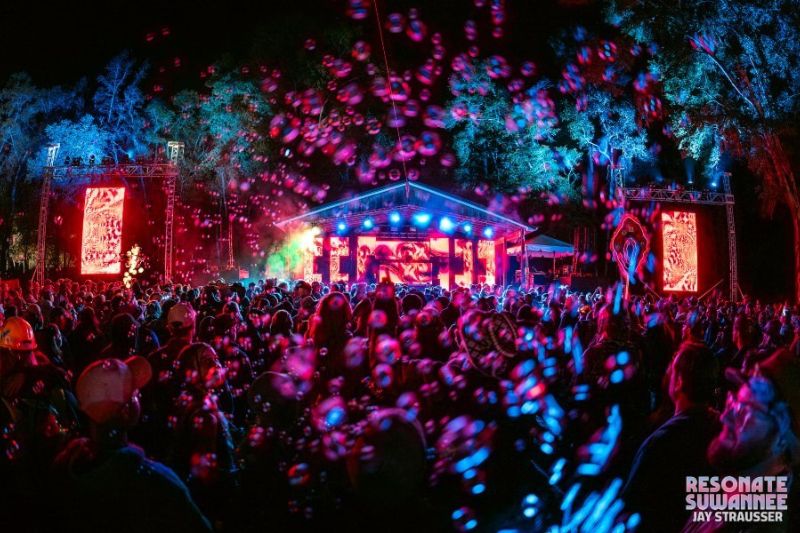 A stage lit with blues, pinks, and greens illuminated a band on stage at the Resonate Suwannee event in Suwannee County, Florida.